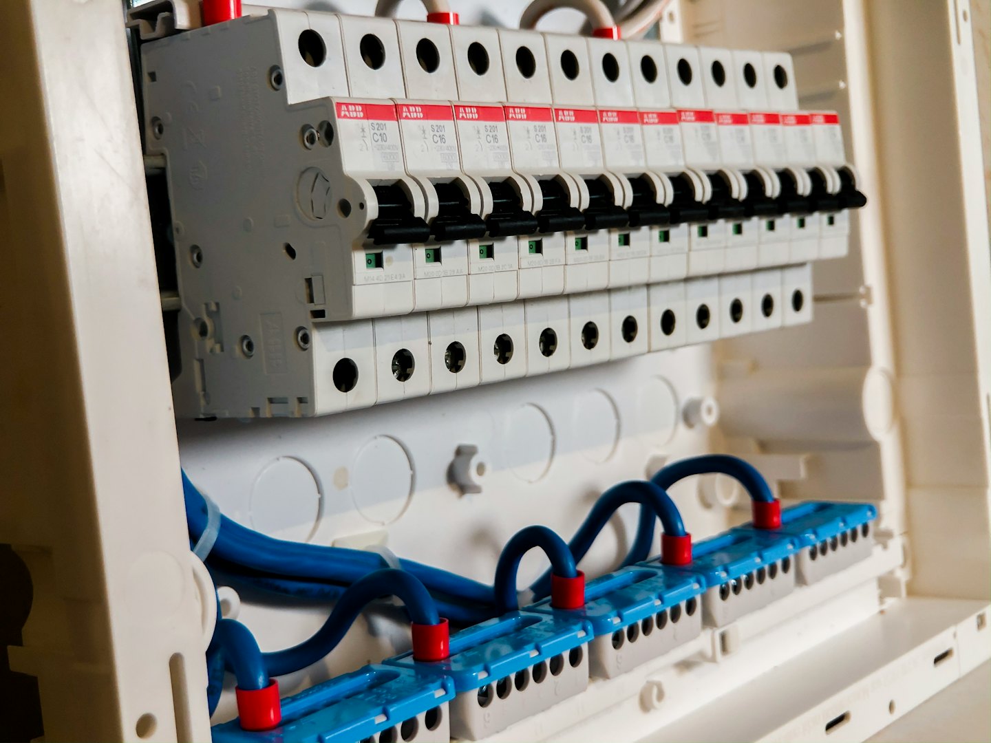 Electrical distribution board with rows of circuit breakers and blue wiring.